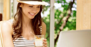Digitale Nomaden Jobs - Frau am PC mit Sonnenhut und Drink